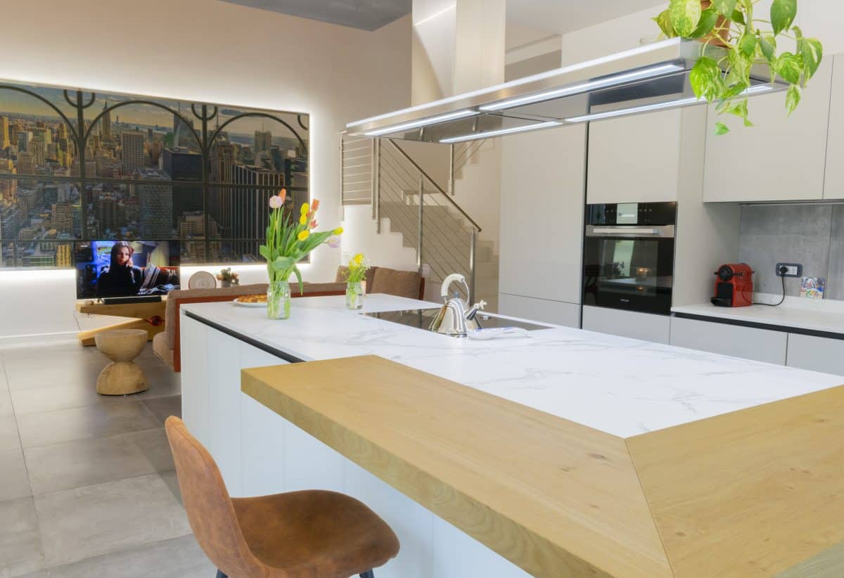 Vista completa della cucina bianca con isola e banco in legno