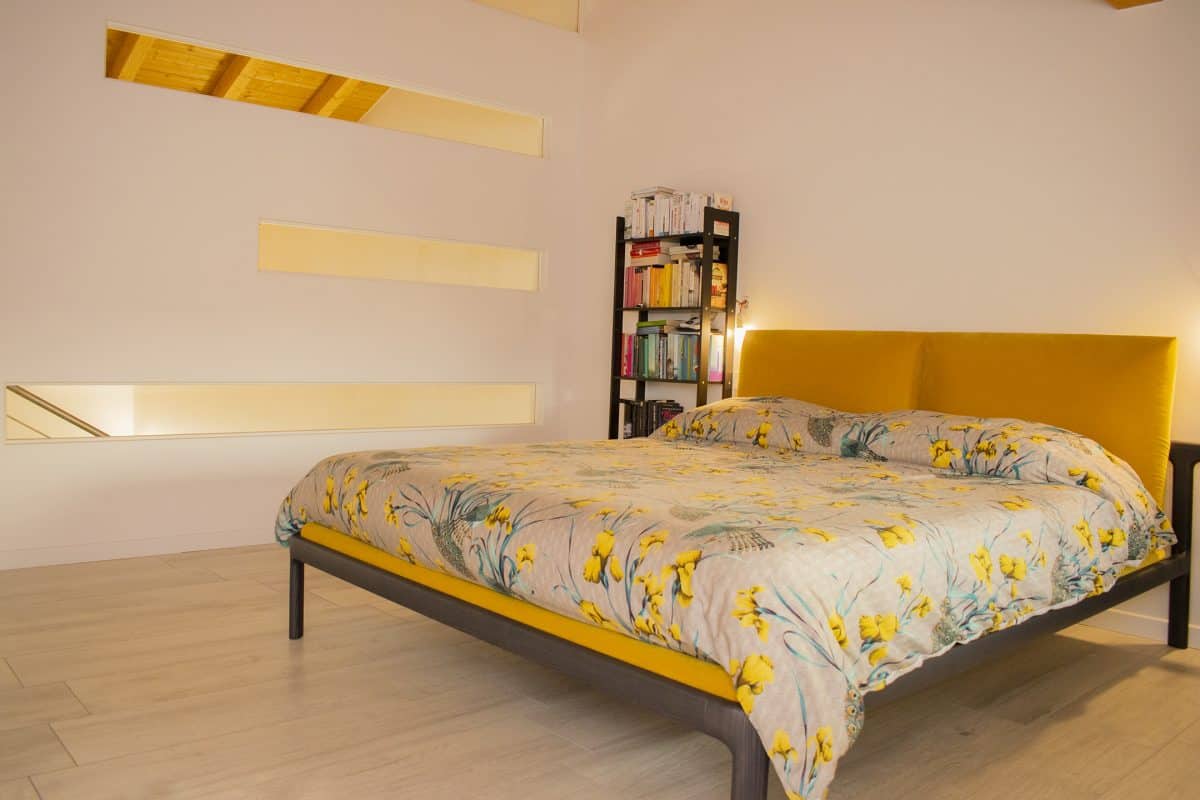 Camera da letto con testiera gialla e arredi essenziali